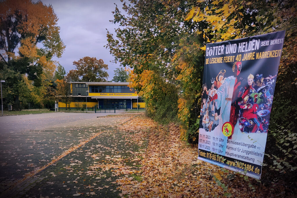Außenfoto des Kultur und Freizeit Zentrums (KFZ) in Neupetershain. Im Vordergrund ist das NCC-Plakat mit dem Motto und den wichigsten Terminen zu sehen.
